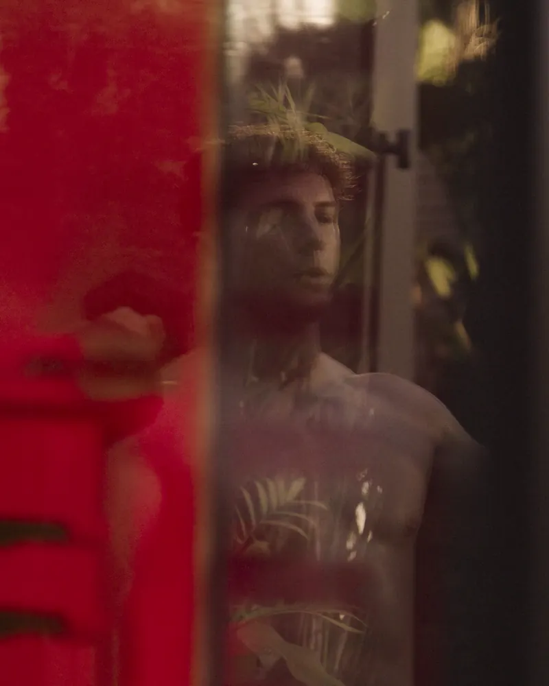 A man in a Peak sauna seen through red-lit glass