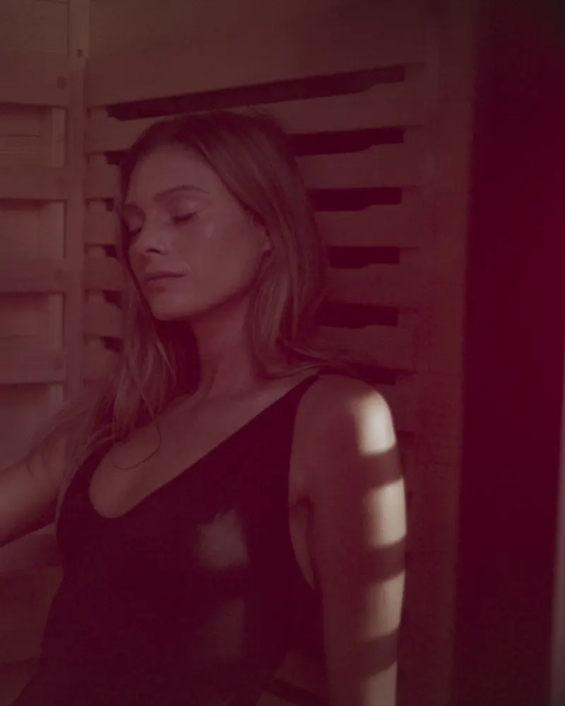 A woman resting in a PEAK sauna lit by red light